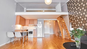 A modern kitchen with wooden cabinets, a white refrigerator, and a dining area with two chairs. - Hotell Ronja (Vimmerby)