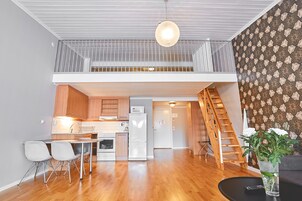 Una cocina moderna con armarios de madera, un refrigerador blanco y una zona de comedor con dos sillas.