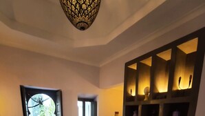 Una sala de estar con una mesa de centro de vidrio, un sofá, un televisor sobre un mueble bajo y un mueble decorativo de pared.