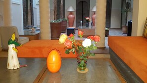 Un vestíbulo con un sofá, una mesa con un florero y una estatua decorativa de un pájaro.