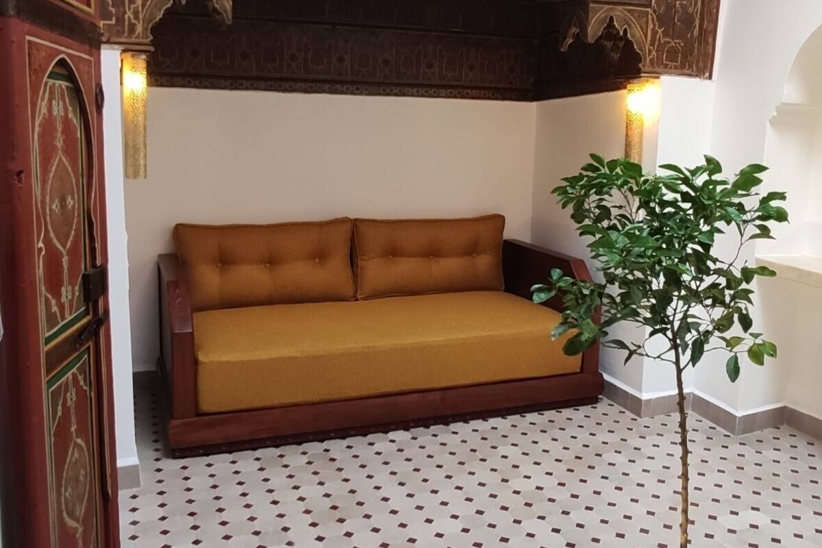 A room with a patterned floor, a sofa, a potted plant, and decorative wall elements.