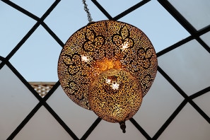 A hanging decorative light fixture with intricate patterns. - Dar Andamaure (Marrakech)