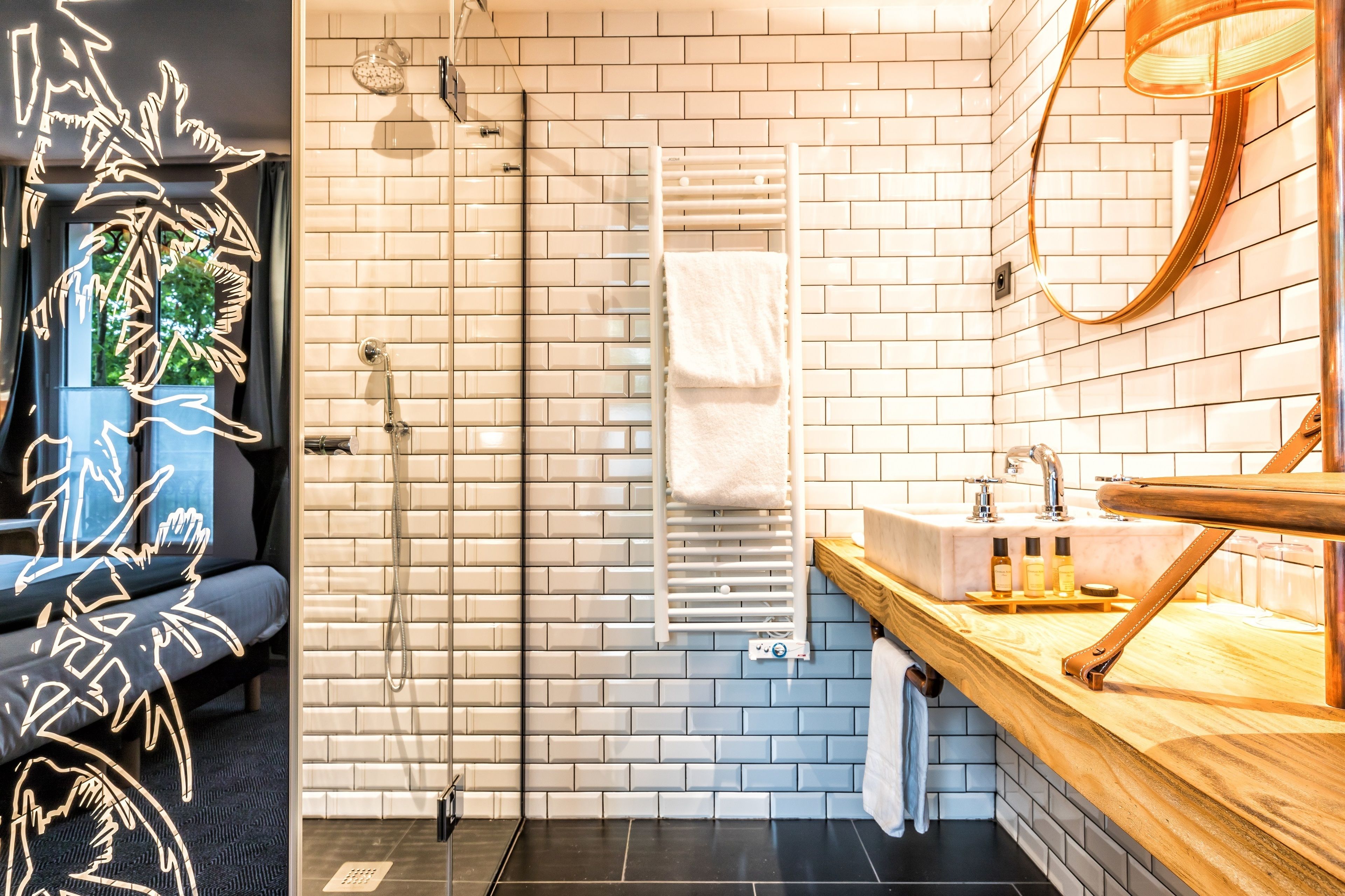 Een moderne badkamer met een glazen douchecabine, een witte handdoekhouder en een houten wastafelmeubel met een wastafel.