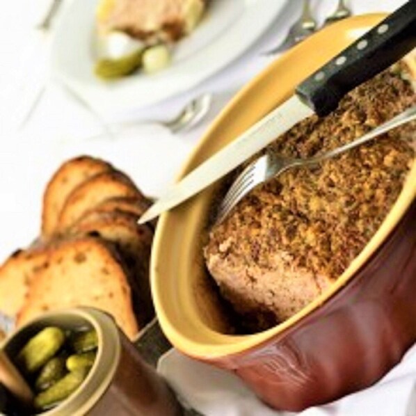 Prato de carne em recipiente amarelo, com faca e garfo ao lado, acompanhado de batatas em rodelas e picles.