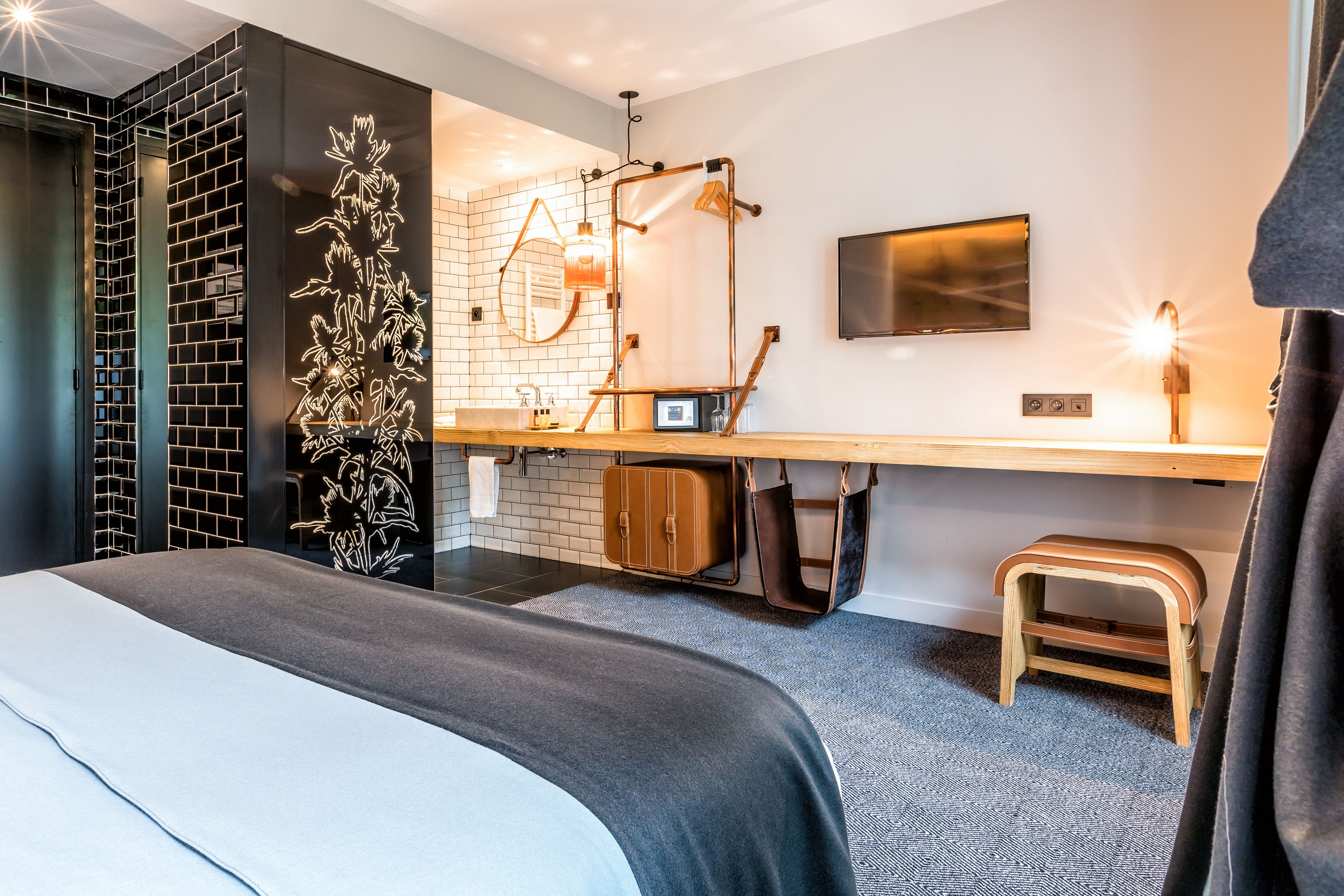 Una habitación de hotel moderna con una cama grande, un escritorio con computadora, un espejo y un televisor.