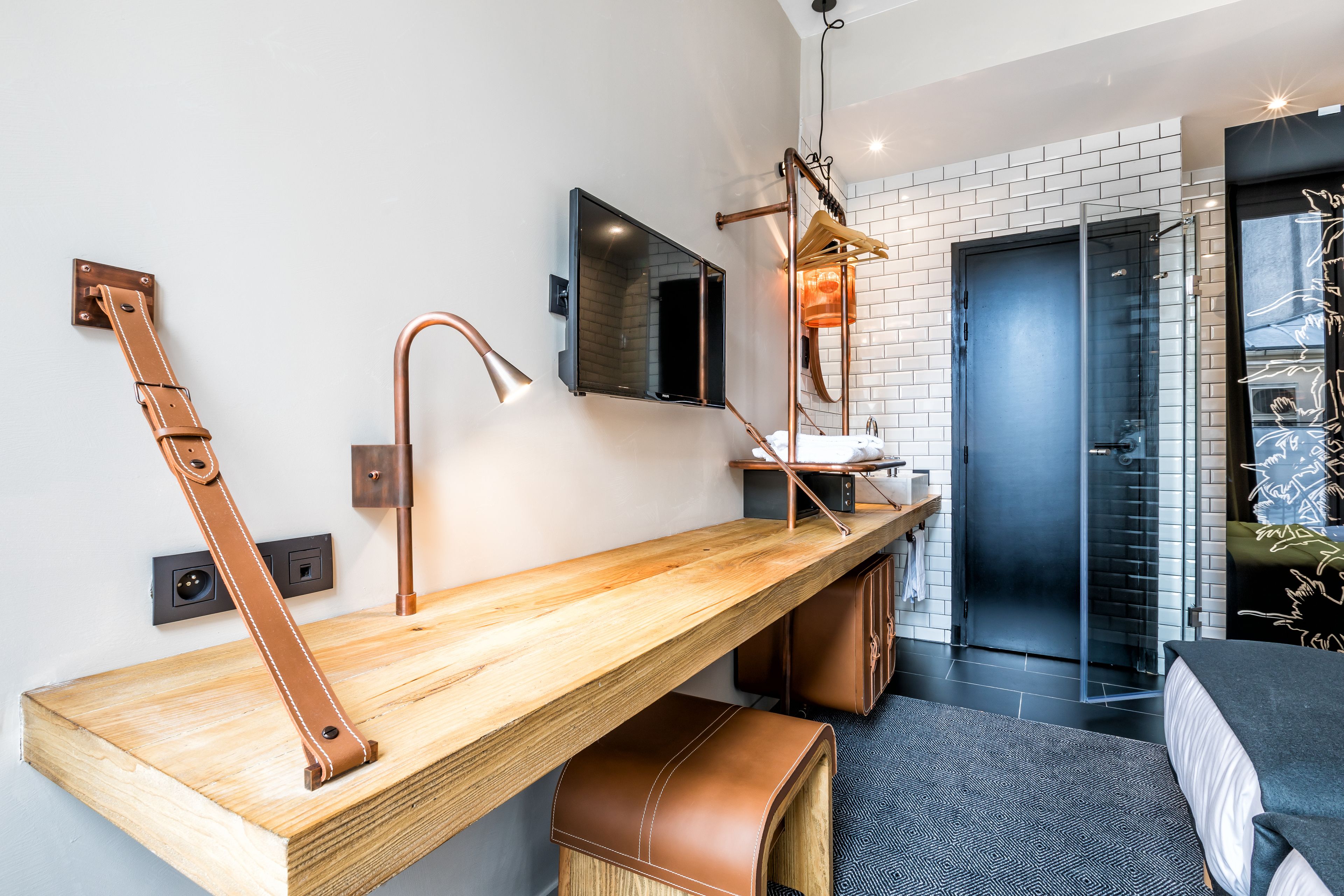A modern bathroom with a wooden vanity, copper fixtures, a mirror, and a shower area.