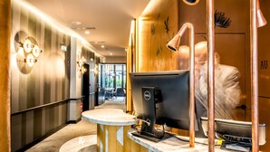 Eine moderne Hotelhalle mit einer Rezeption, einem Dell-Computer und einem großen Spiegel, der eine Person reflektiert.