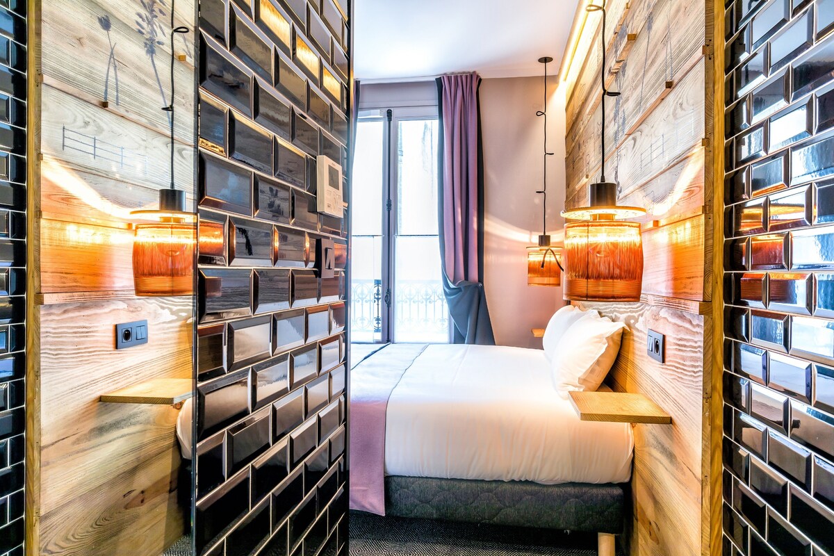 Ein Hotelzimmer mit einem grossen Bett, Holzpaneelen an der Wand und zwei Pendelleuchten.