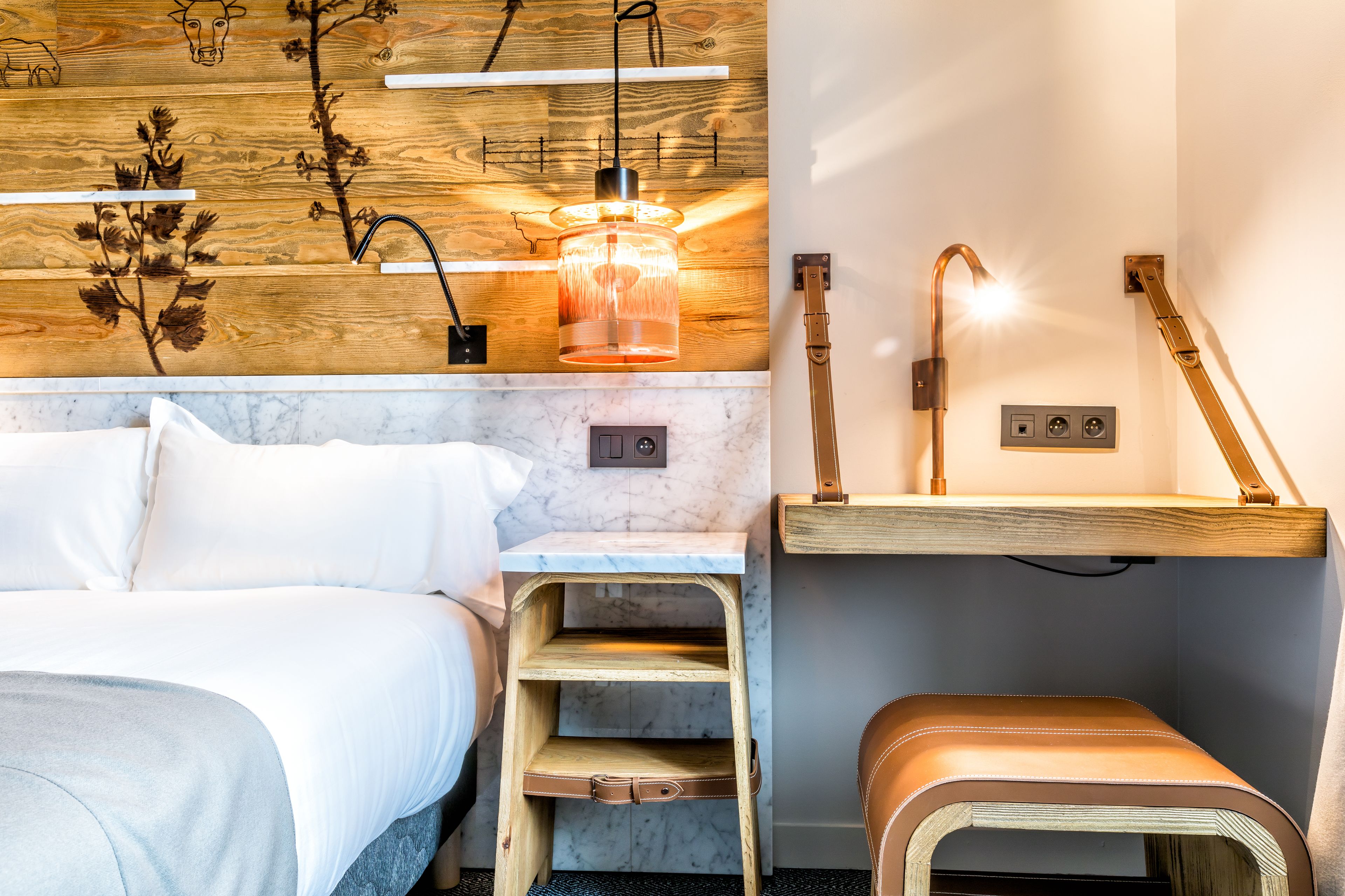 A modern bedroom with a bed, wooden shelves, a bench, and a wall-mounted light fixture.