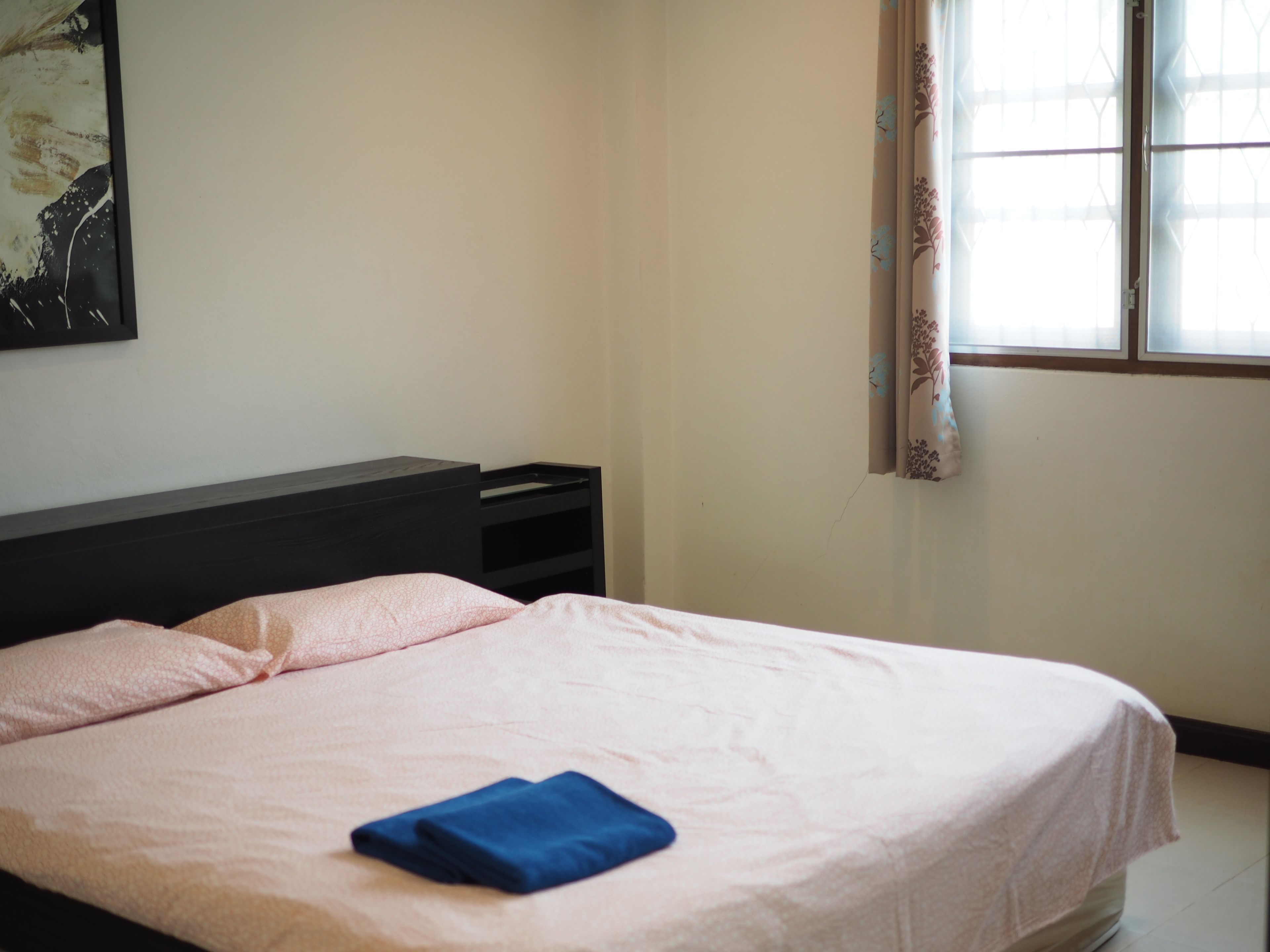 A bedroom with a bed, a nightstand, and a window with curtains.