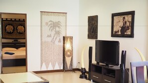 A modern living room with a bed, a TV, and decorative items.