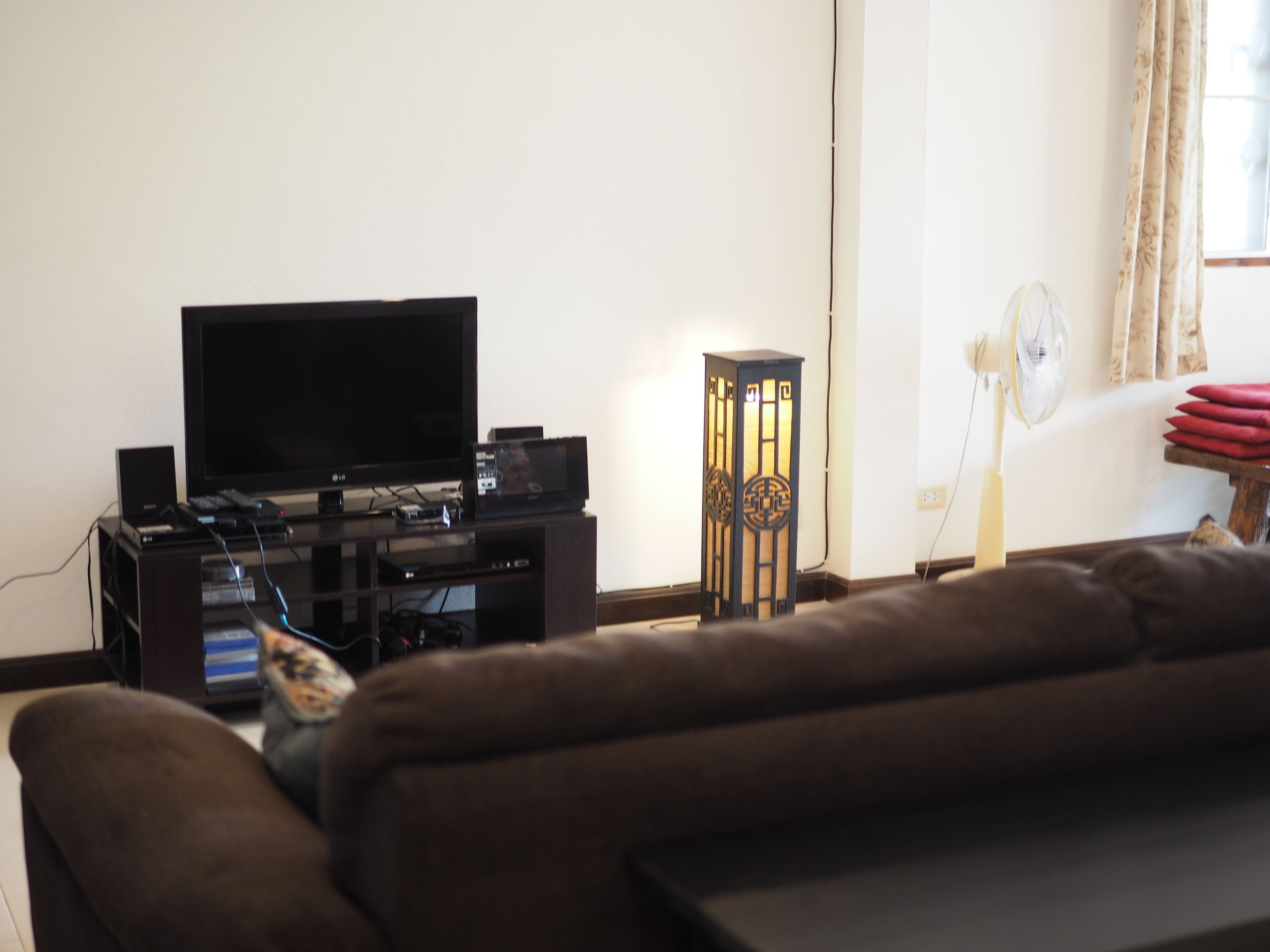 Una sala de estar con televisor de pantalla plana, equipo de sonido, lámpara de pie decorativa y sofá.