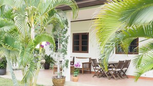 A patio area with outdoor furniture, potted plants, and a white building with a tiled roof.