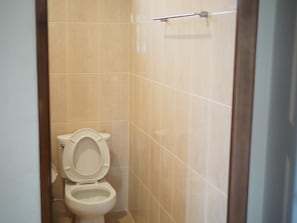 A small, clean bathroom with a toilet and a towel rack on the wall.