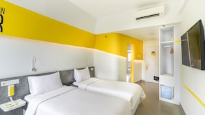 Een hotelkamer met twee bedden, een televisie, een kledingkast en een badkamer.