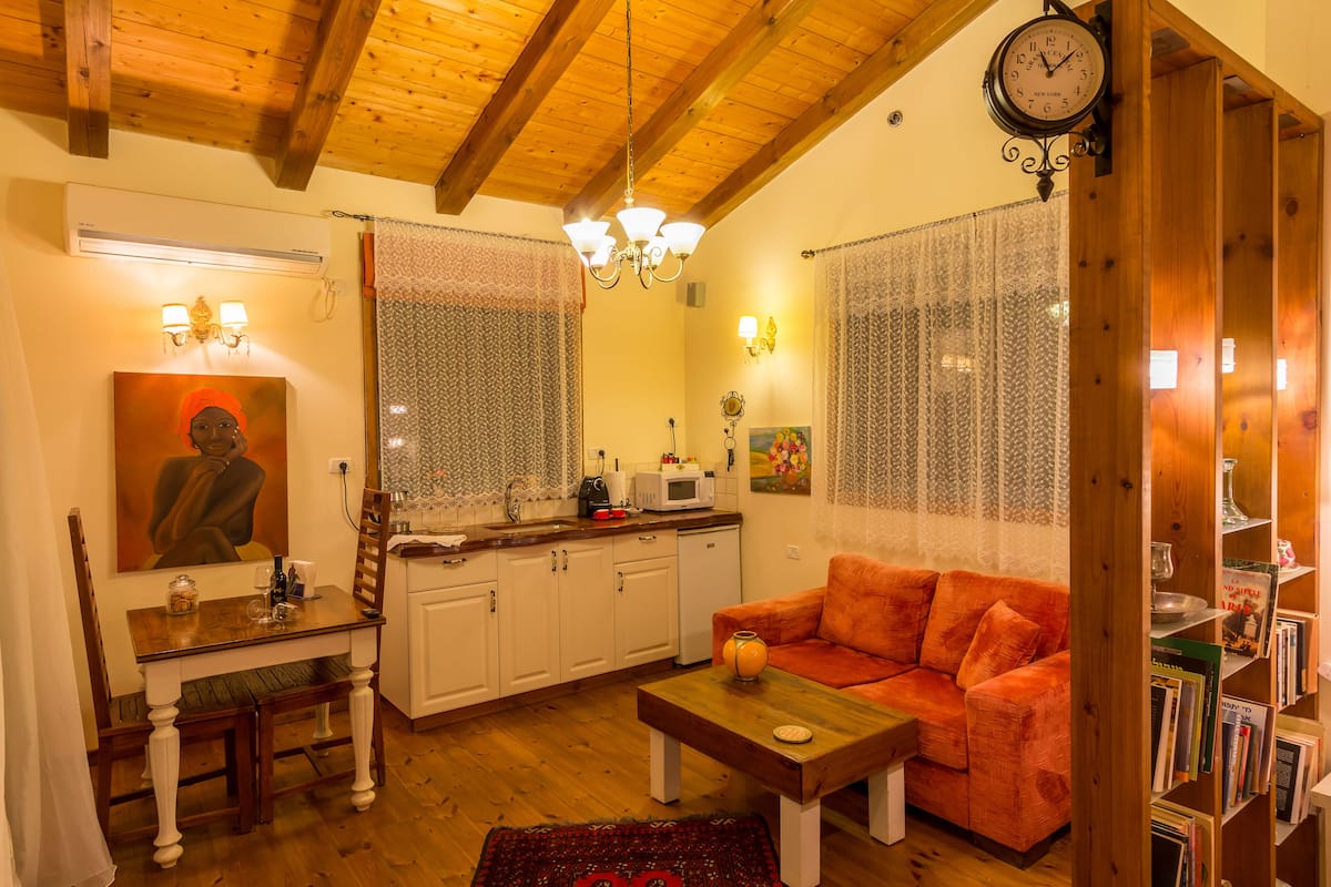 A cozy living room with a wooden ceiling, a sofa, a coffee table, and a bookshelf.