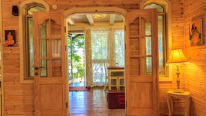 A wooden interior with a wooden door, a table, and a lamp. - Betzel Haella (Mevoot HaHermon)
