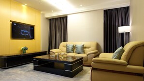 A modern living room with a flat-screen TV mounted on the wall, a sofa set, a coffee table, and a lamp. - Seaman Hotel Guangzhou (Guangzhou)