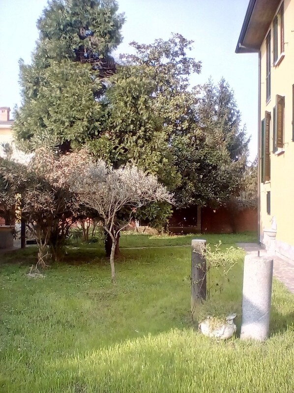 A grassy courtyard with trees and a building. - Locanda I Tarocchi (Vailate)