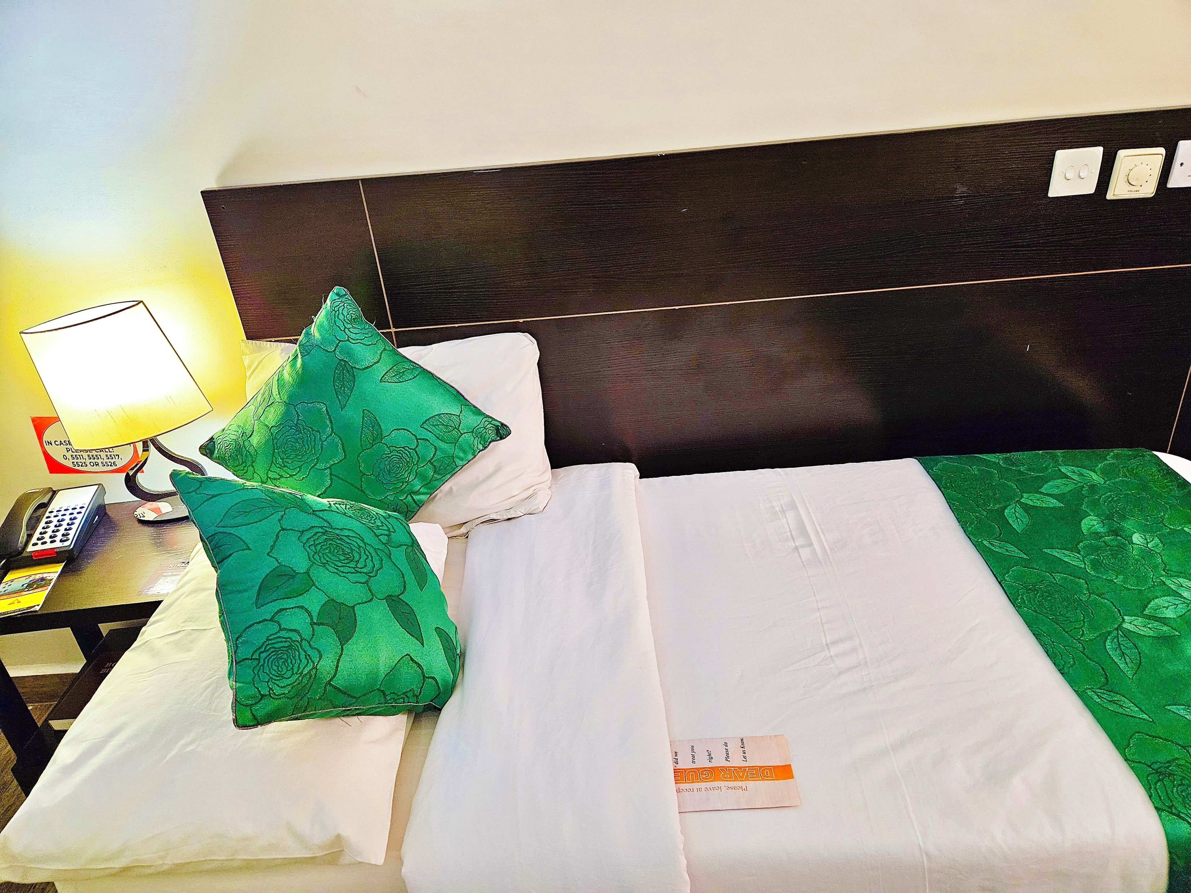 A hotel room with a bed, a nightstand, a lamp, and a telephone.