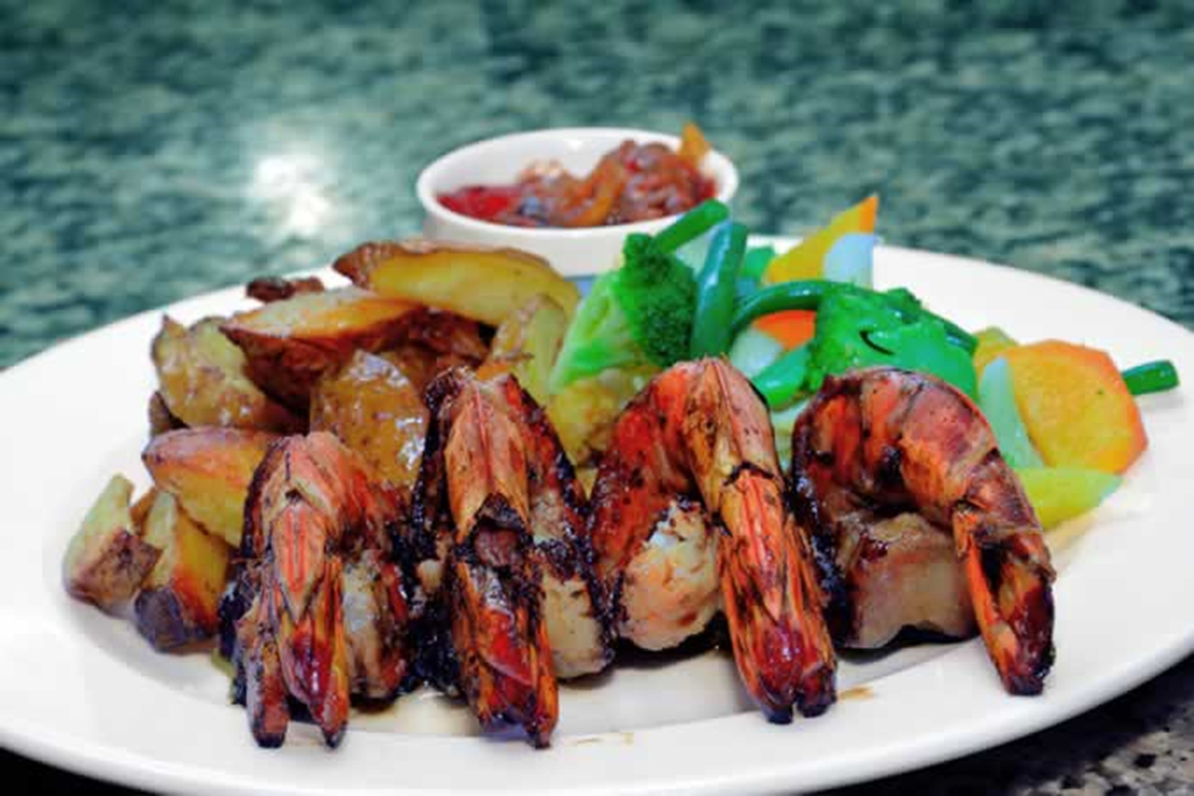 A plate of grilled seafood with potatoes and vegetables.