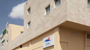 A building with a beige facade, multiple windows, and a sign for "Soho Eilat". - Soho Eilat (Eilat)