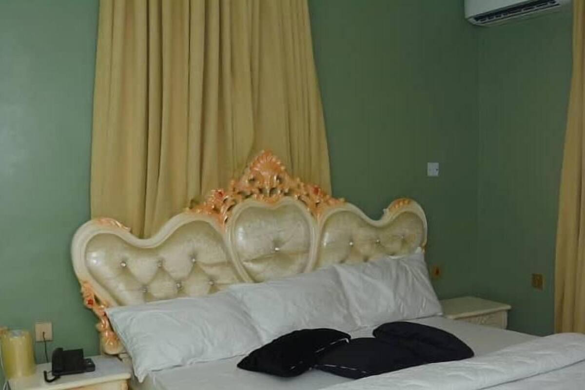 A bedroom with a large bed, a nightstand, and a wall-mounted air conditioner.