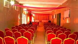 A conference room with rows of red chairs and a stage at the front.