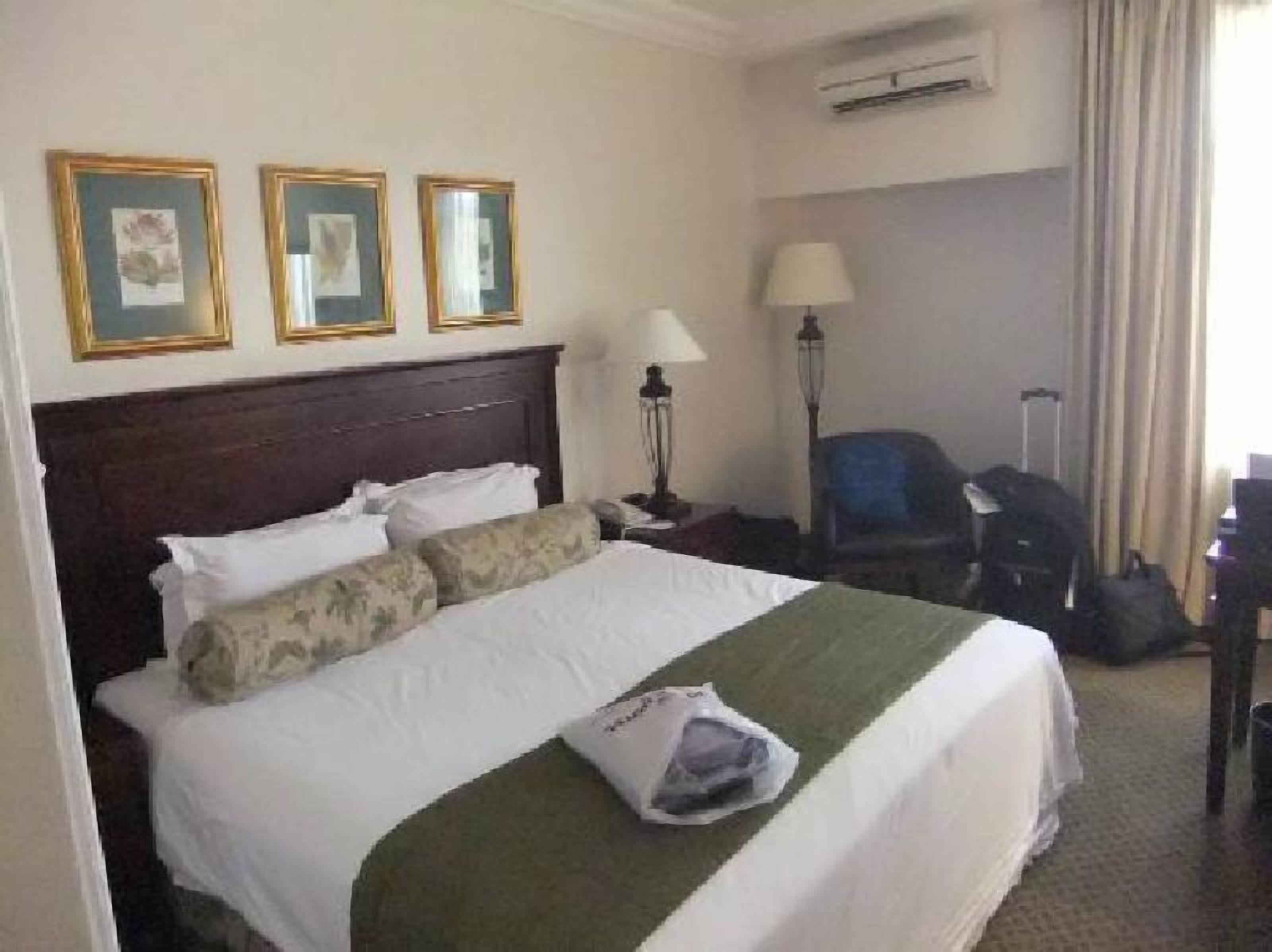 Habitación de hotel con una cama grande, una mesita de noche, una lámpara, una silla y un escritorio.
