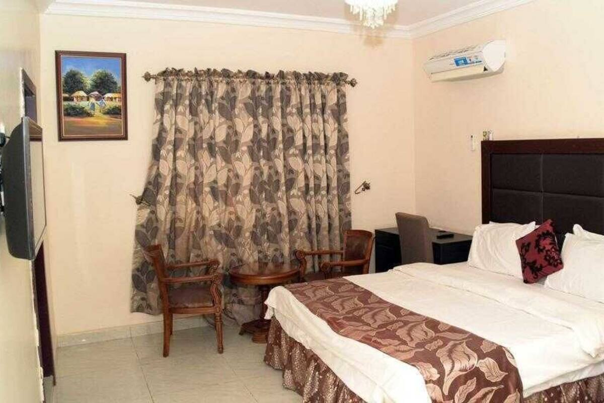 Une chambre d’hôtel équipée d’un lit, d’un bureau, d’une chaise, d’une télévision et d’une fenêtre avec des rideaux.