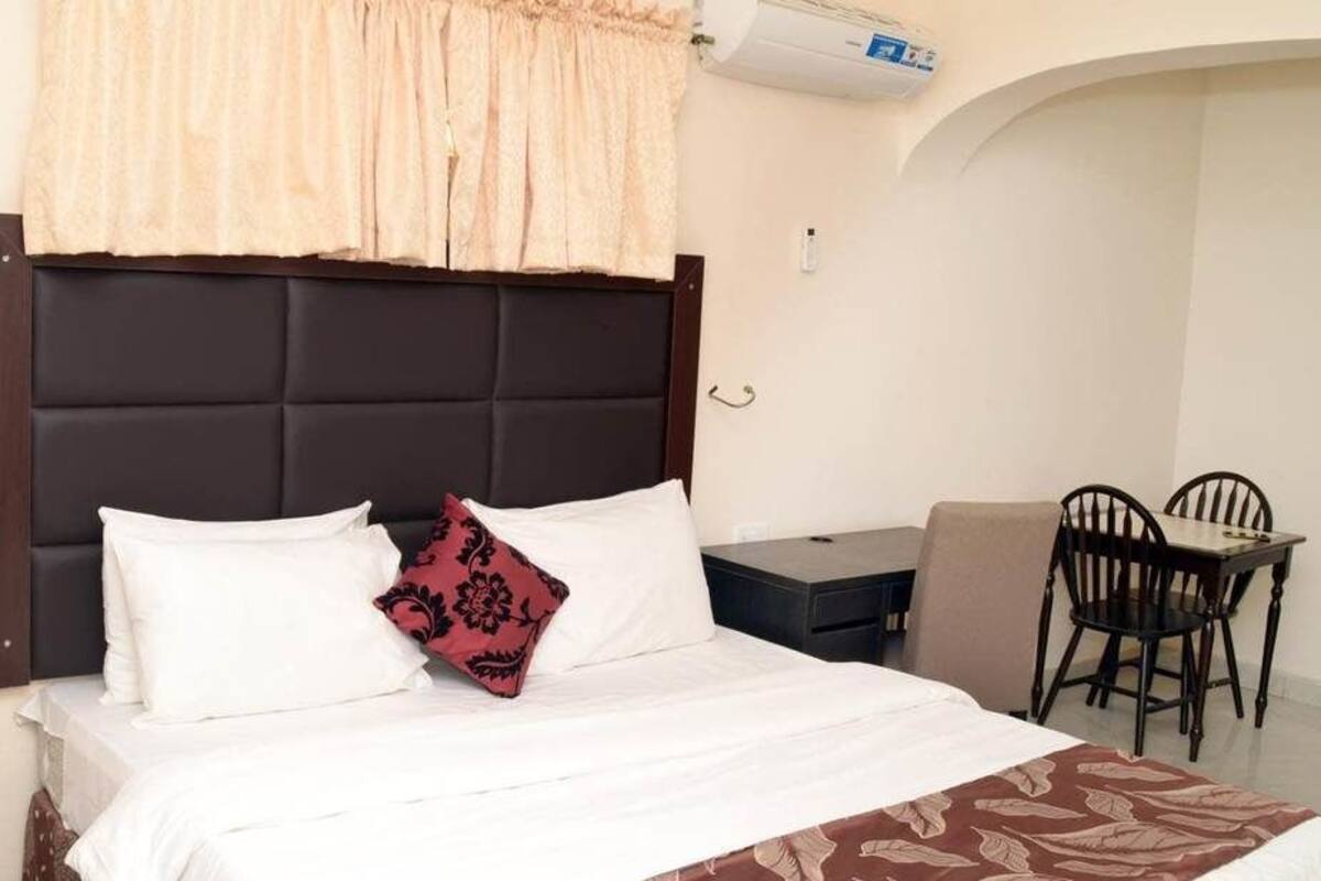 Une chambre d’hôtel comprenant un lit, une table de chevet, une lampe et un petit bureau avec une chaise.