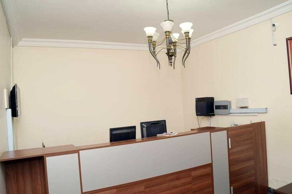 A reception desk with a chandelier, a flat-screen TV, and a microwave on the wall.