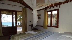 A bedroom with a bed, a window, and a view of the beach. - Laguna Blu - Resort Madagascar (Andavadoaka)