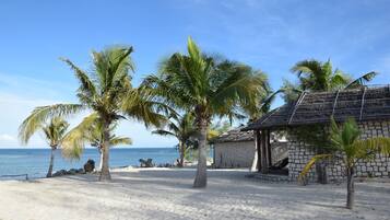A beach scene with palm trees and a thatched-roof building.