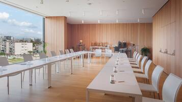 A conference room with a long table, white chairs, and a wooden wall.