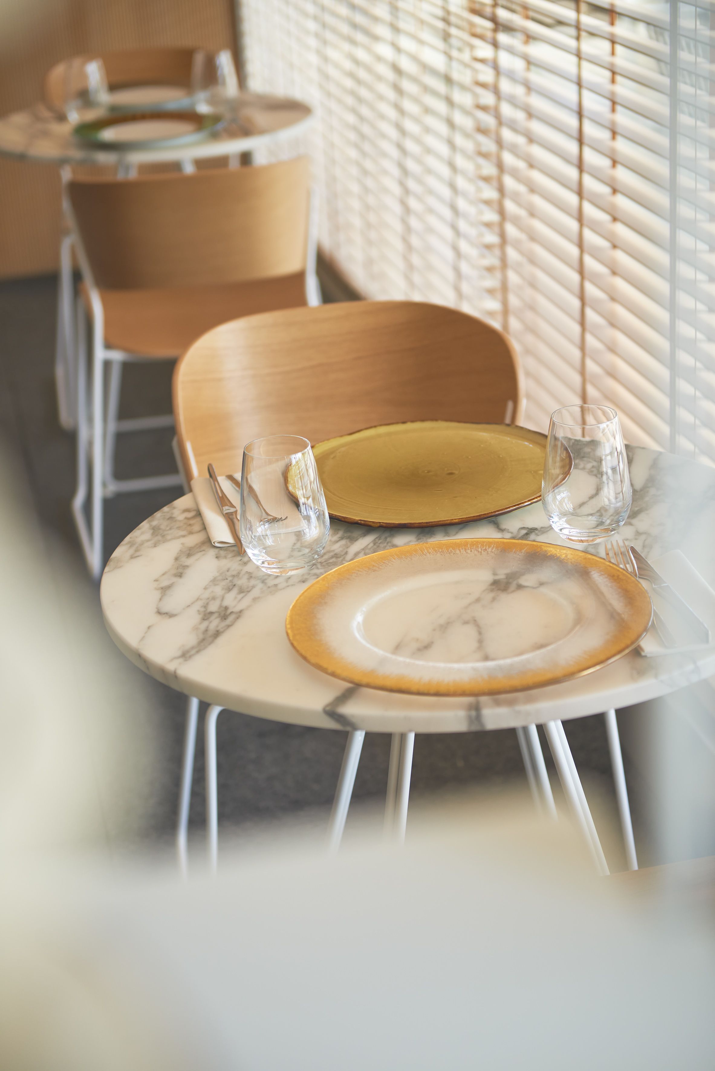 Un comedor con mesas y sillas redondas, algunas con platos y cubiertos.