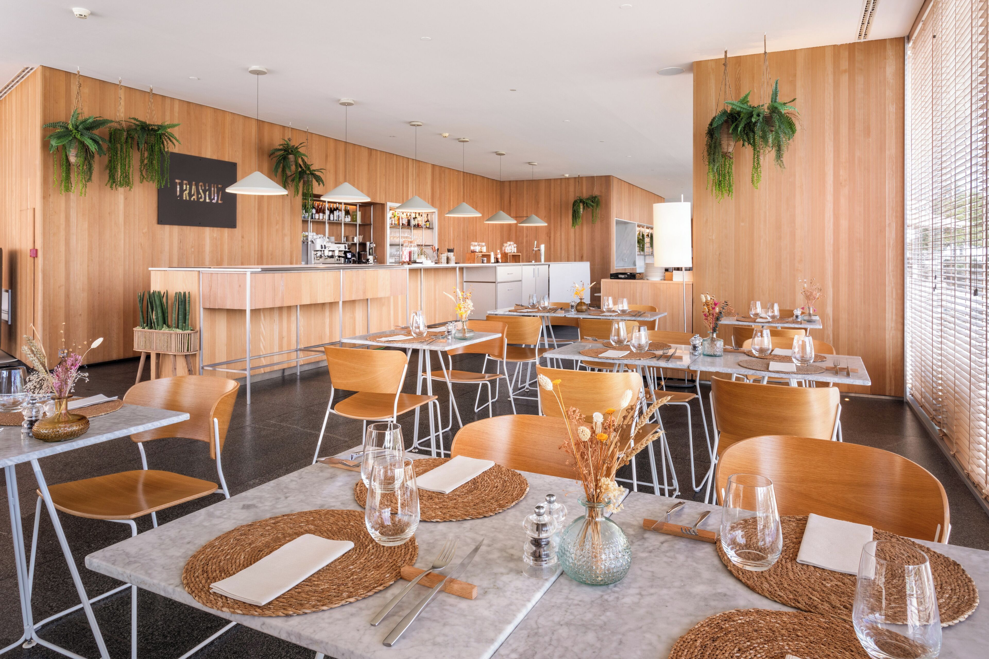 Un restaurante moderno con paredes de madera, varias mesas y sillas.