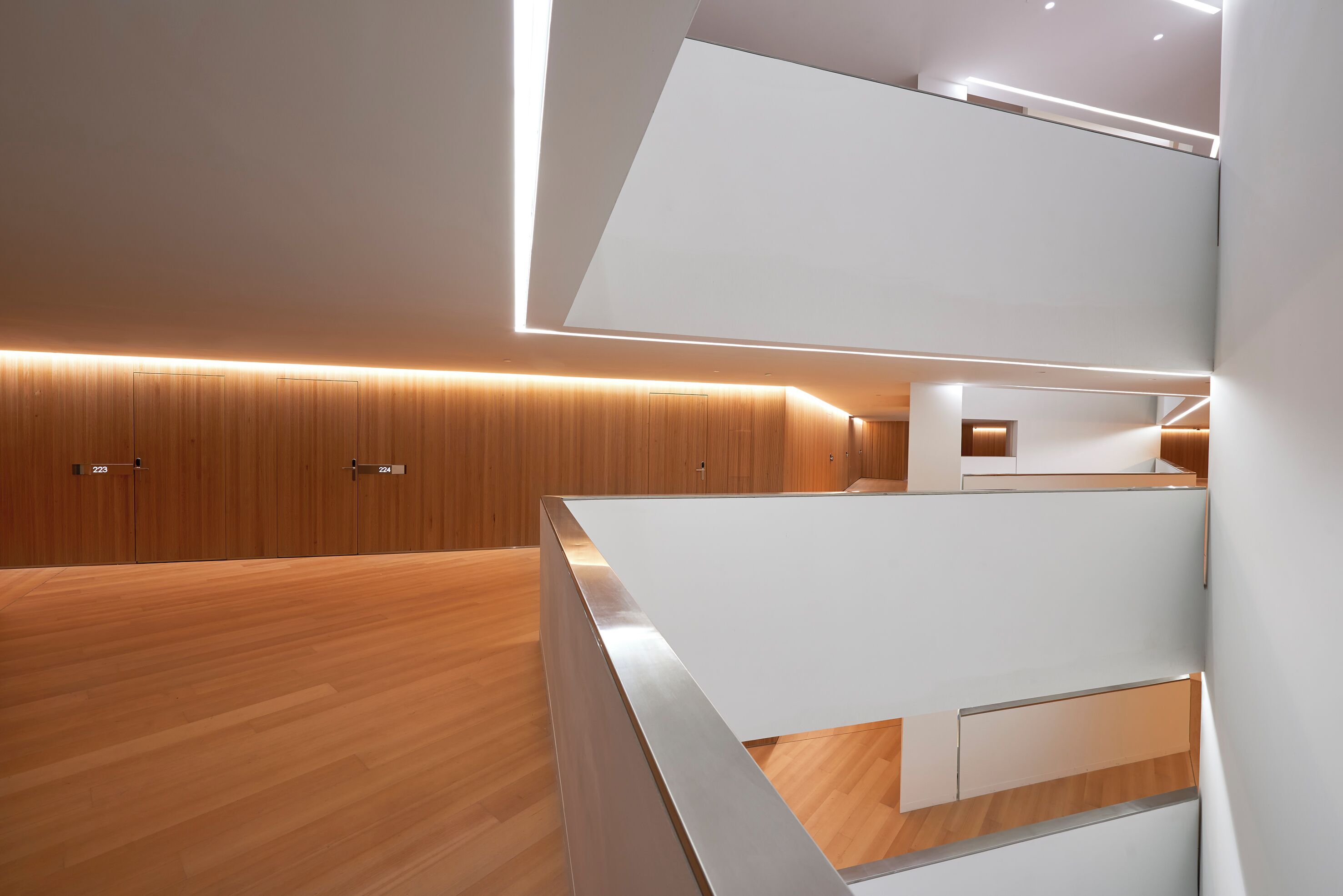 Un interior moderno con suelo de madera, paredes blancas e iluminación empotrada.