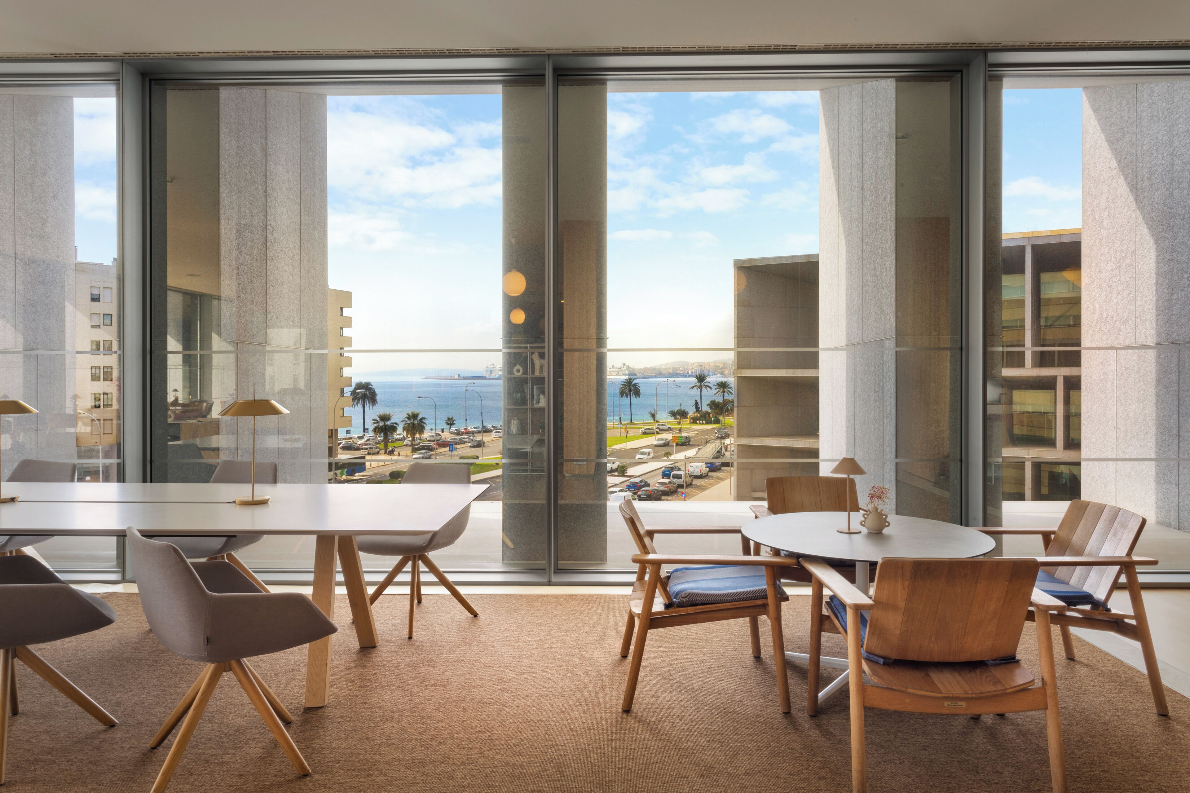 Une salle de conférence moderne, dotée de grandes fenêtres, offrant une vue sur la mer et sur le paysage urbain.