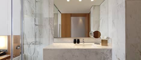 A modern bathroom with a glass-enclosed shower, a marble countertop, and a large mirror.