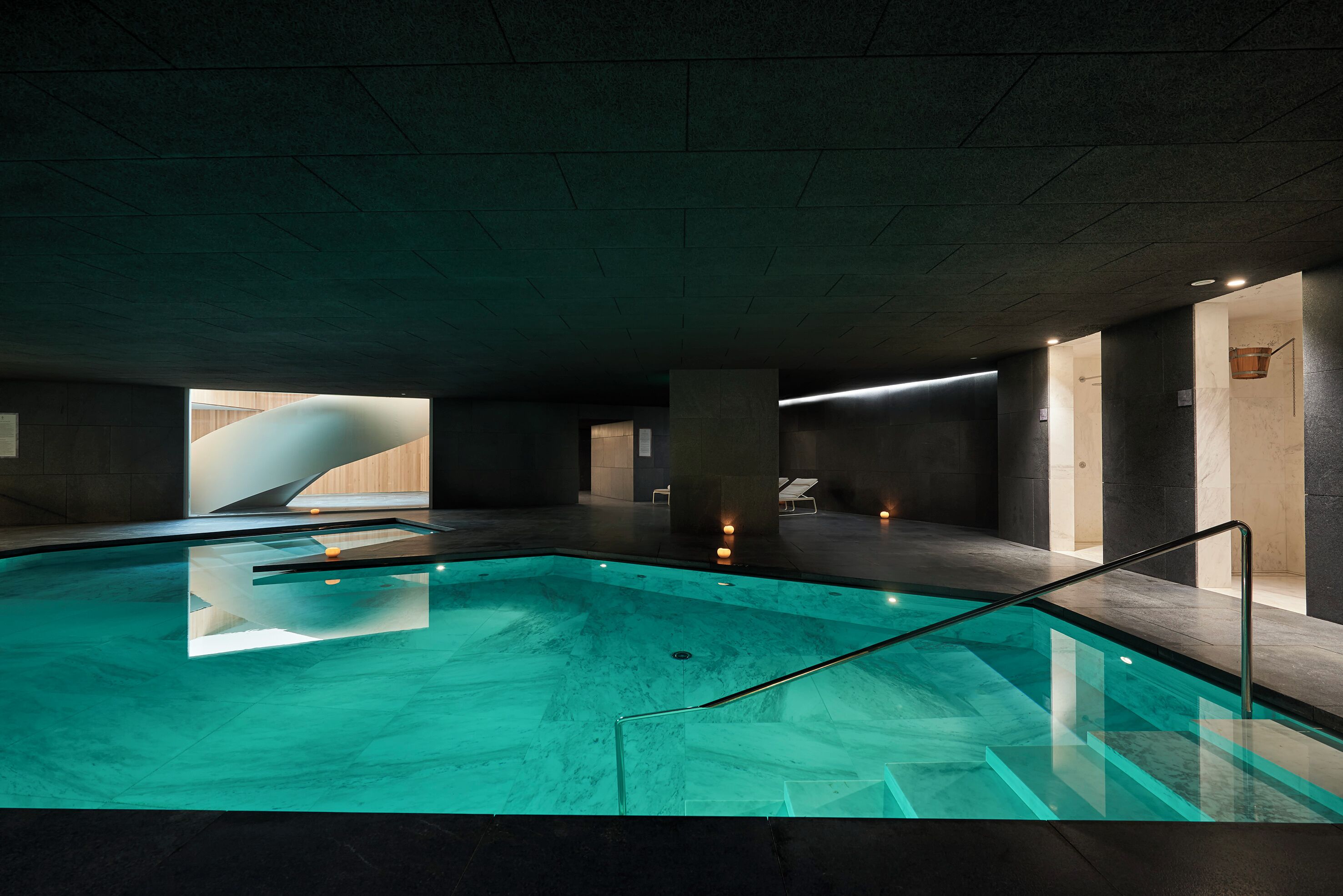 Una piscina interior con agua cristalina, una barrera de cristal y un diseño arquitectónico moderno.