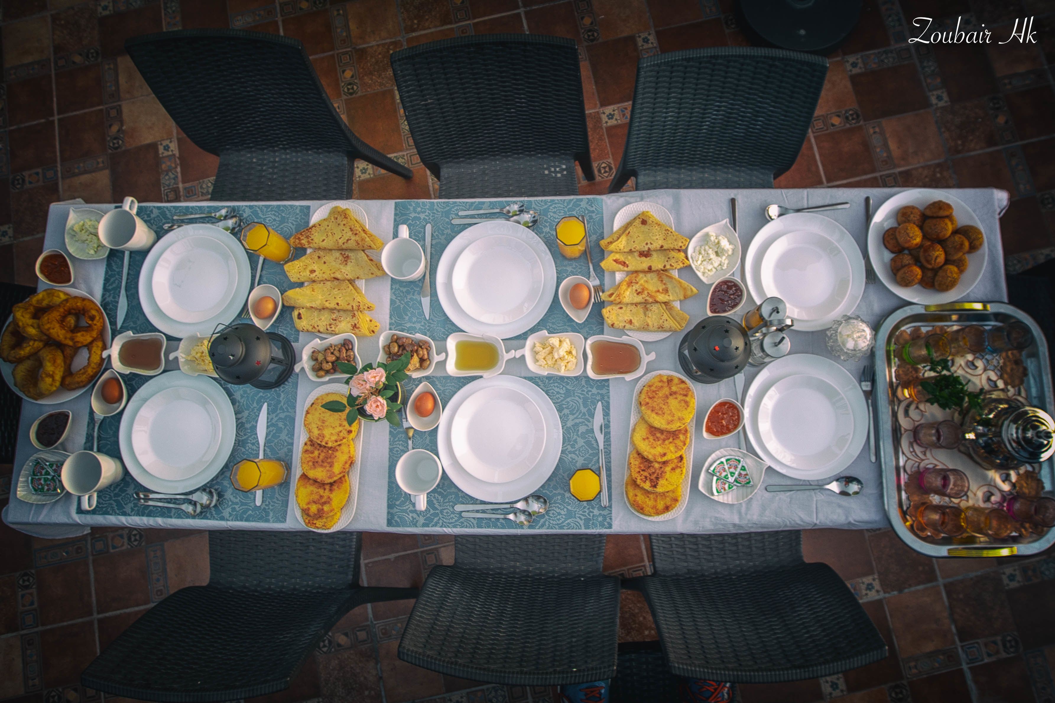 A dining table set with various dishes, plates, and utensils, surrounded by chairs.