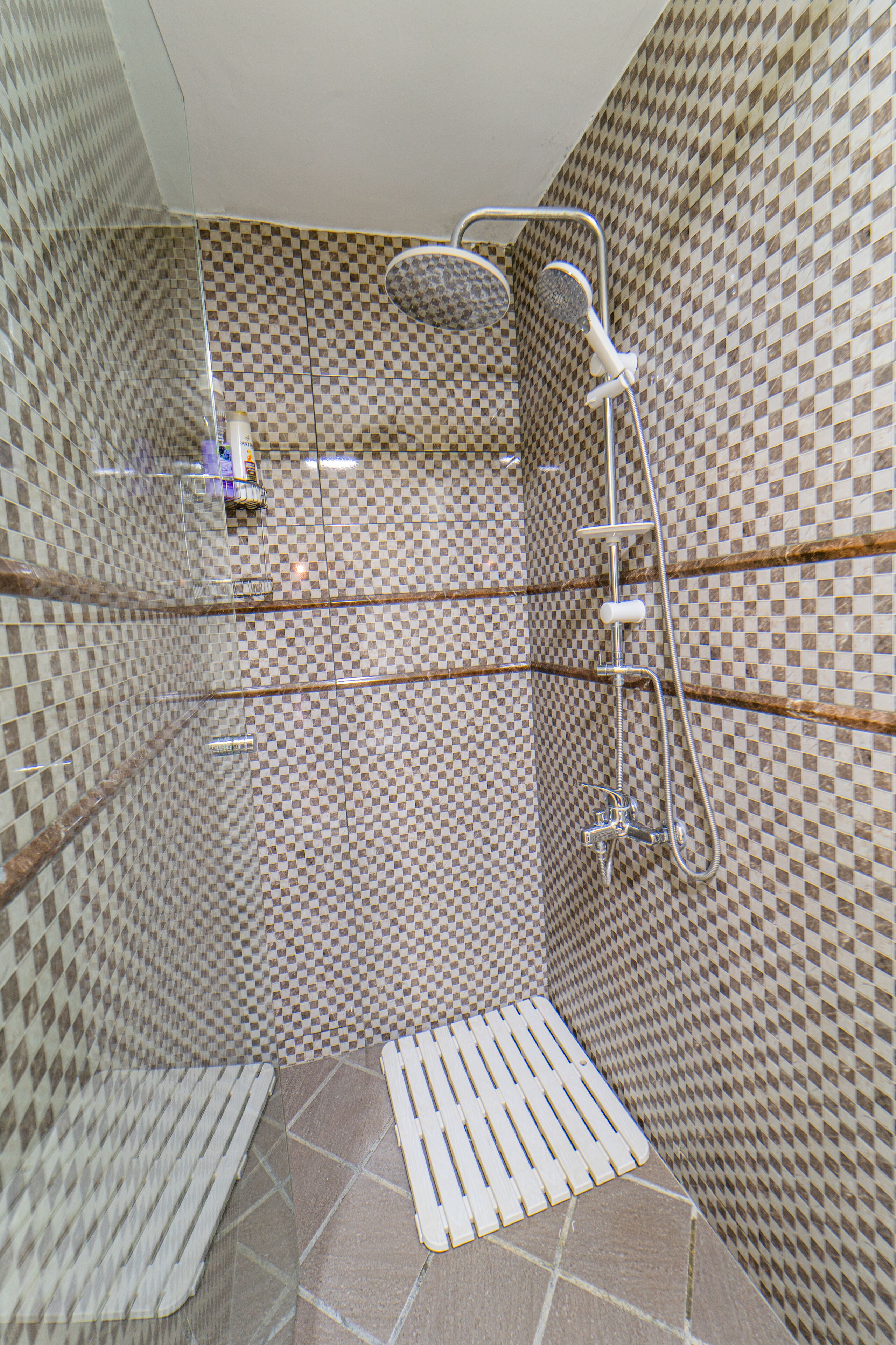 A shower area with a checkered tile pattern, a handheld showerhead, and a handheld shower attachment.