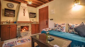 Una sala de estar acogedora con chimenea, vigas de madera, un sofá con cojines estampados y una mesa de centro.