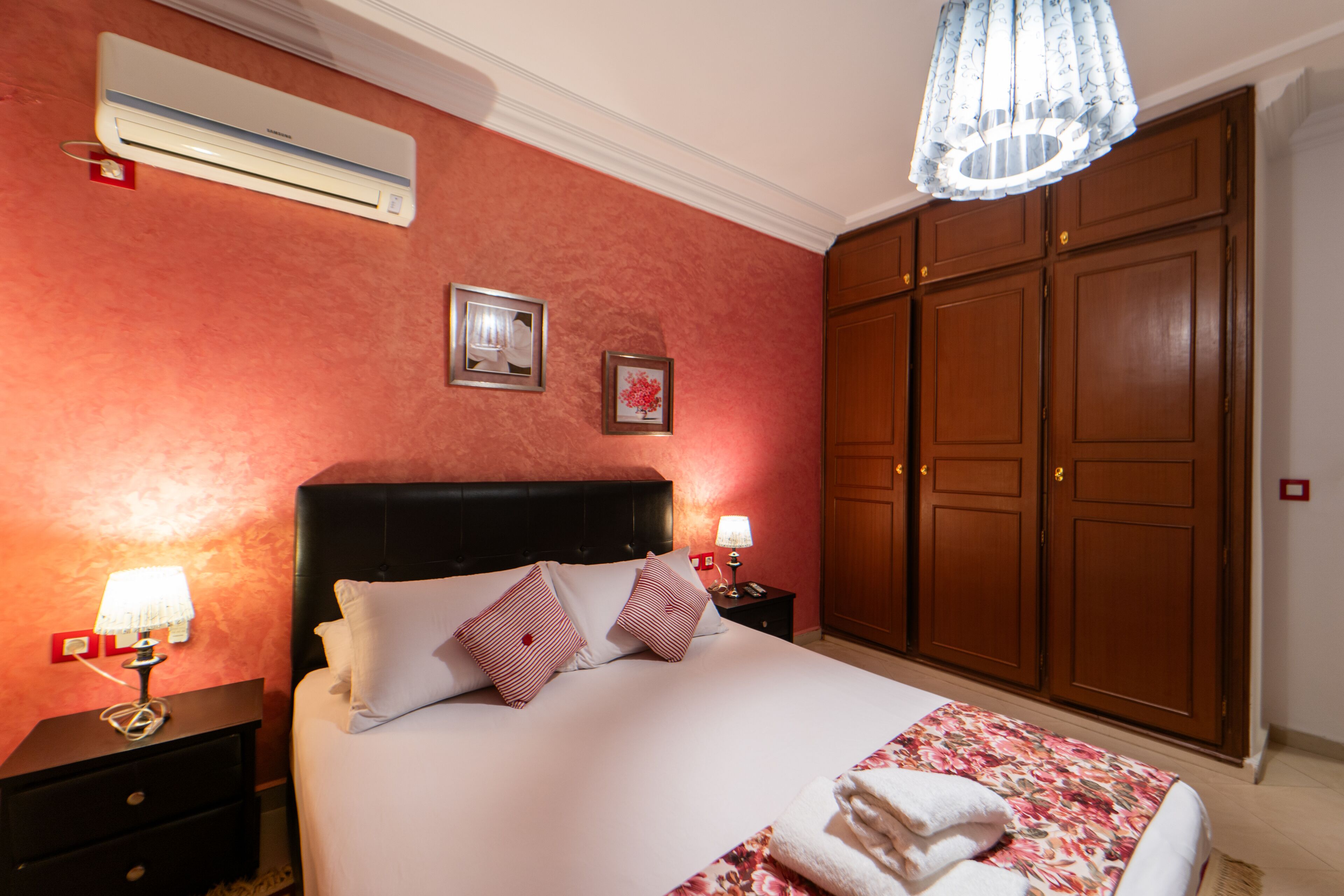 A hotel room with a large bed, a wardrobe, and an air conditioning unit.