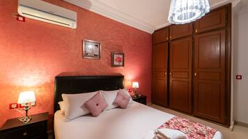 A hotel room with a large bed, a wardrobe, and an air conditioning unit.