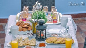 Una mesa de desayuno dispuesta con diversos alimentos, bebidas y vajilla.