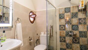 Un baño con cabina de ducha de vidrio, lavamanos e inodoro.