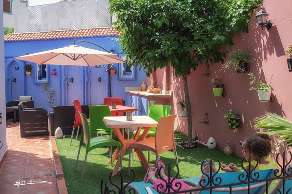 A patio with outdoor seating, a table, and a large umbrella.