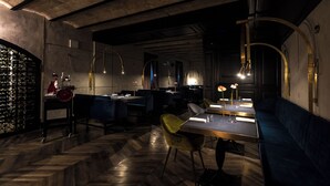 A dimly lit restaurant with a herringbone floor, dark wood furniture, and pendant lighting. - Hotel The Haven Roma (Rome)